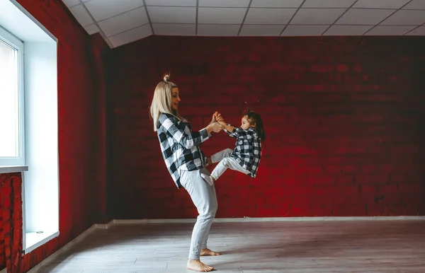 Joven madre y su hija haciendo ejercicios de yoga juntos en el gimnasio — Foto de Stock