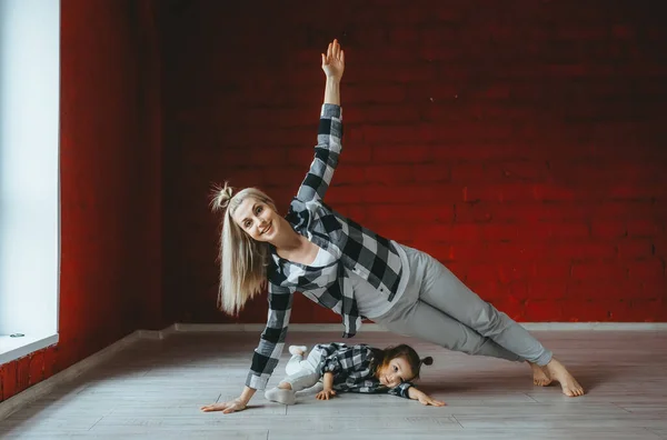 Kobieta robi ćwiczenia z małą córką na siłowni — Zdjęcie stockowe