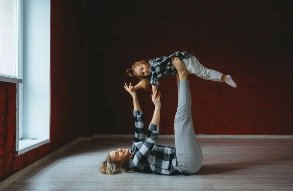 Ung sportig mamma och liten flicka som stretchar gymnastikövningar tillsammans i loft studio — Stockfoto