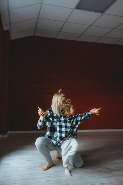 Mutter und Tochter tanzen in identischer Kleidung in der Turnhalle. Sportliche Familie — Stockfoto