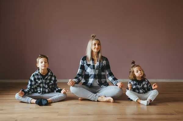 Junge Familie aus Mutter und Kindern Sohn und Tochter beschäftigen sich mit Yoga, Bewegung im Fitnessstudio. — Stockfoto