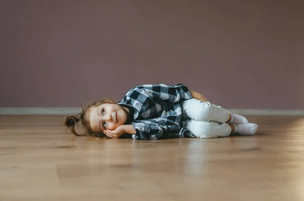 Retrato divertido de niña linda acostada en un piso interior — Foto de Stock