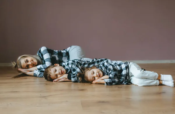 Top view of mother and her two kids in identical clothes lying on floor with closed eyes. — Stock Photo, Image