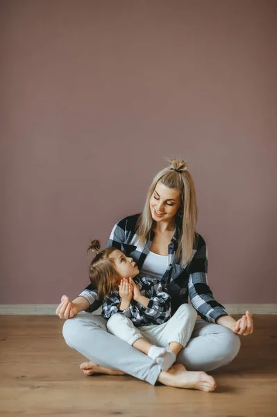 Мать с ребенком практикует йогу в позе лотоса, и они смотрят друг на друга. Горизонтальный портрет — стоковое фото