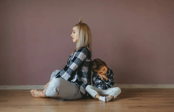 Mother sitting in lotus pose and her little daughter sit and sleep on floor. Side view — Stock Photo, Image