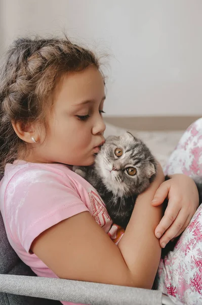 Belle petite fille embrassant un mignon chaton écossais. Vue latérale . — Photo