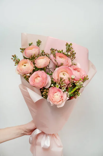 Mano de mujer sosteniendo hermoso ramo de rosas rosadas frescas sobre el fondo gris . — Foto de Stock