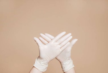Kahverengi arka planda beyaz eldiven giyen iki el. Virüsü durdur. Kavramsal fotoğraf.