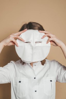 Yüzün derisini nemlendirmek için yüz maskesi tutan güzellik uzmanı. Yakın plan portre