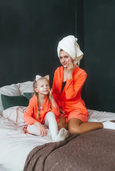 Mãe Filha Felizes Roupões Banho Com Máscara Creme Sentado Cama — Fotografia de Stock