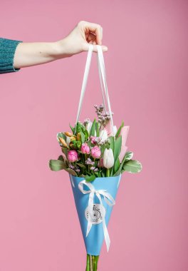 Güzel bir buket lale ve mavili güller pembe arka planda bir kadının elinde. Sevgililer Günü için moda afiş, Uluslararası Kadınlar Günü veya Anneler Günü.