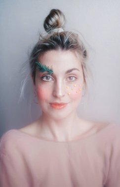 Duman altı stüdyo geçmişine karşı yaratıcı makyajlı güzel bir genç kadın. Sanat kaşları ve kirpikleri, bir ağaç dalı. Dikey portre