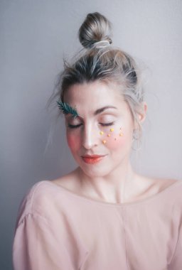 Stüdyonun sisli geçmişine karşı yaratıcı makyajı ve kapalı gözleri olan güzel genç bir kadın. Sanat kaşları ve kirpikleri, bir ağaç dalı. Dikey portre