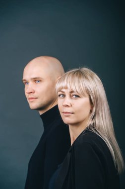 Profil görüntüsü: Mavi gözlü yakışıklı kel adam ve stüdyoda aynı yöne bakan sarışın kadın..