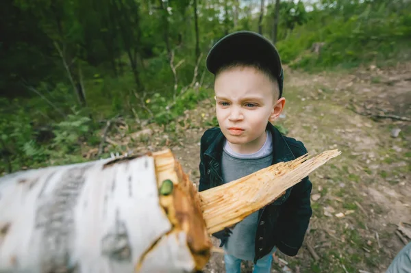 Mały Chłopiec Grymasem Twarzy Czapce Stoi Tle Drewna Opałowego Kłód — Zdjęcie stockowe