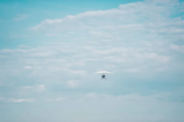 White motor hang glider against the cloudy blue sky
