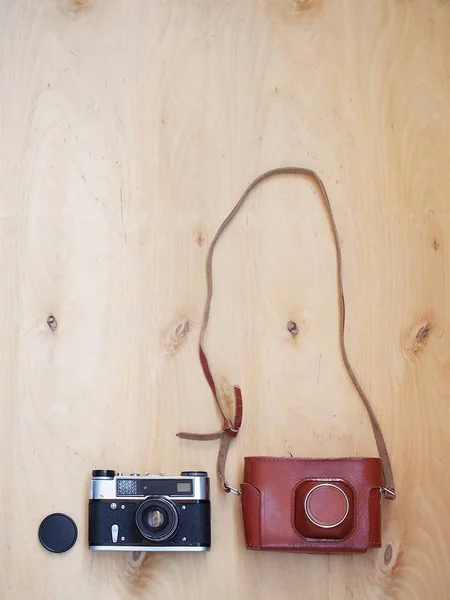 Retro old photo camera with leather case on wooden background