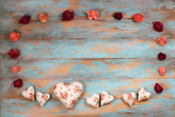 Hearts and wilted roses on wooden background.
