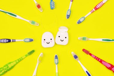 Toothbrushes and dental floss on yellow background clipart