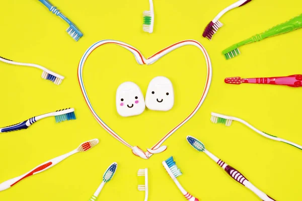 Toothbrushes and dental floss on yellow background