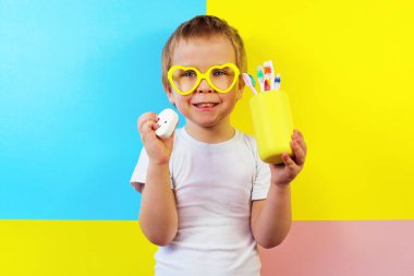 Elinde diş fırçası ve diş ipi olan mutlu bir çocuk. Diş temizleme konsepti.