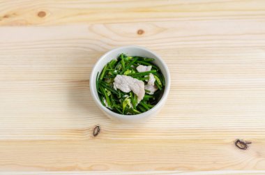 Kızarmış domuz Çin Chives çiçek ve sarımsak ile ahşap arka plan üzerine ilave edin.