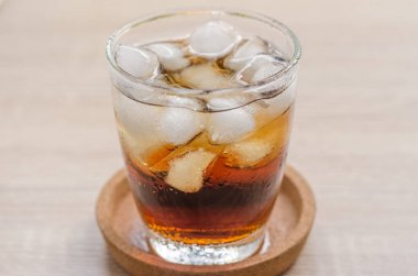 Ahşap arka plan üzerinde buzlu cola bardak