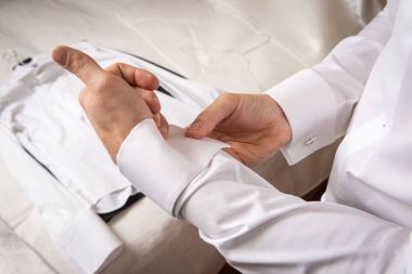 Kol düğmesini tamir eden smokinli bir adamın yakın çekimi.. 