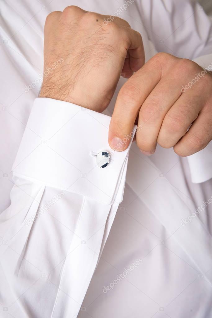 Close-up of a man in a tux fixing his cufflink. 