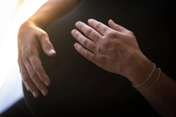 pregnant woman holds her hands on her swollen belly. Love concept.