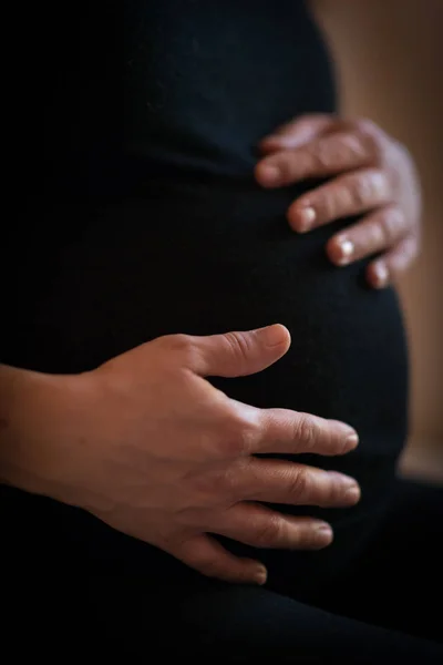 pregnant woman holds her hands on her swollen belly. Love concept.