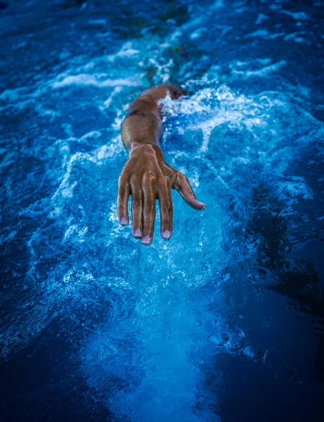 detalle de la mano de una persona nadando en la piscina