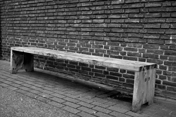 Simple Wooden Bench Cobble Stones Brick Wall Background Black White — Stock Photo, Image