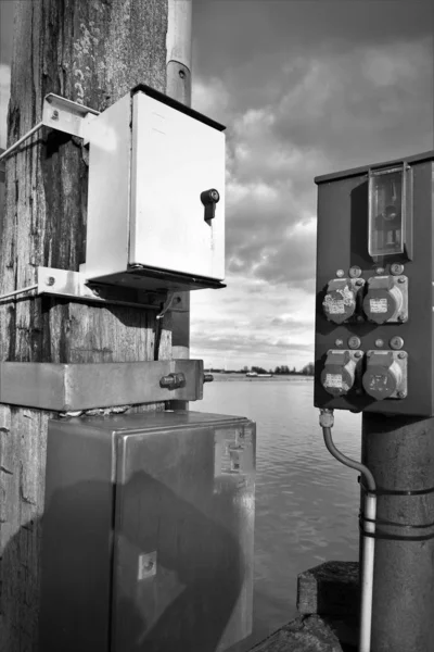 Old industrial power boxes on the river shore in black and white