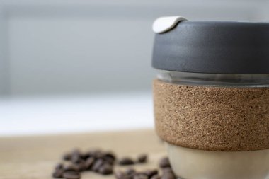 Reusable Coffee Eco Cup. Toughened Glass Cup & Natural Cork Band. Secure silicon lid. Reusable eco cup on a wooden background.Eco-Friendly, Spill Proof Travel Mug with Lid | Black. Keep Cup
