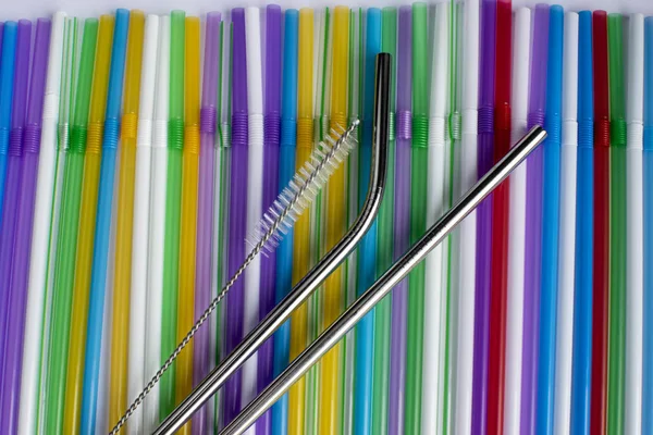 Reusable metal straws with a portable case - stainless steel, an environmentally friendly set of drinking straws with cleaning brushes. Against the background of plastic tubes for a cocktail.