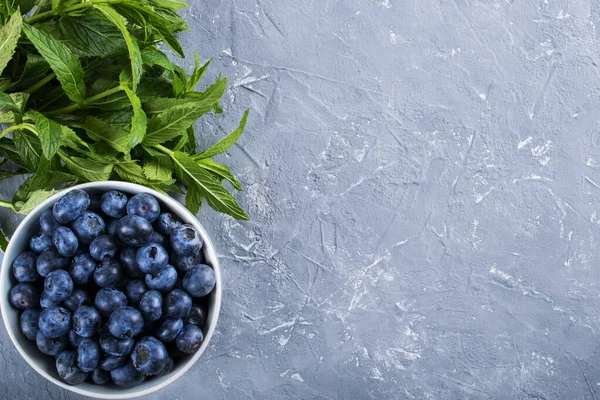Blue berries of blueberry on a white background. Mint leaves. Fresh fruits for a healthy diet