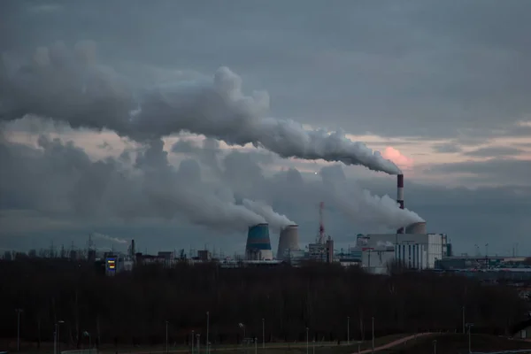 smoking chimneys of a power plant at sunset