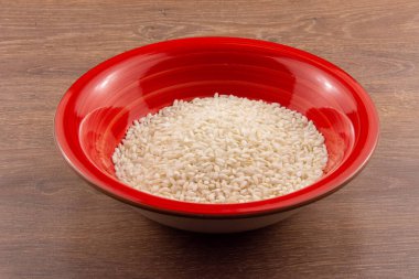 Tahta arka planda izole edilmiş bir kasede pirinç.