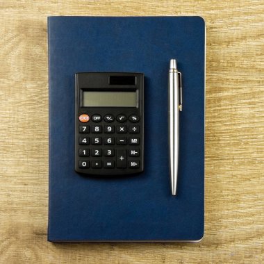 Tahta zemin üzerinde defter, kalem, hesap makinesi Üst görünüm, düz uzanma