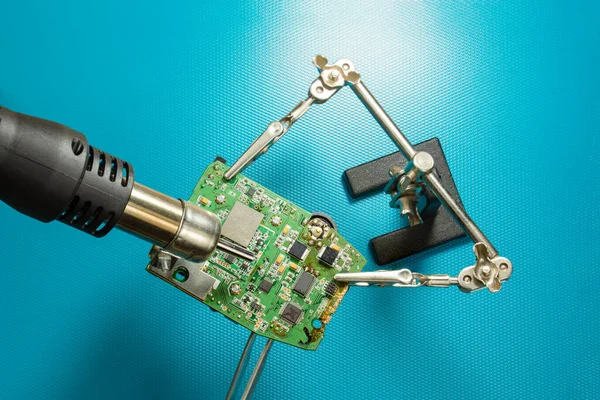 Repair of electronic devices and printed circuit boards. Soldering and desoldering of  electronic components. Engineers repair circuit board with soldering iron and hot air gun. Top view