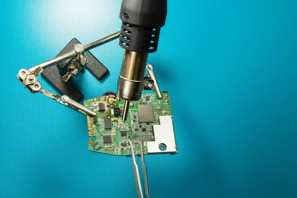 Repair of electronic devices and printed circuit boards. Soldering and desoldering of  electronic components. Engineers repair circuit board with soldering iron and hot air gun. Top view