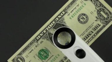 Bir dolarlık banknot dönüyor. D. Washington 'ın büyütülmüş bir portresi bir dolarlık banknotun üzerinde büyüteçle. Üst görünüm.