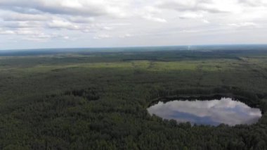 Hava aracı güzel bir orman gölü üzerinde çekim yaptı. Gökyüzü göle yansıyor.