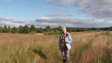 Uzun otların arasında bir yol boyunca yürüyen köylü bir kızın insansız hava aracı görüntüleri.