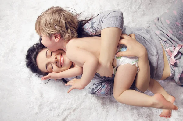 Glückliche Mutter und Sohn umarmen und lachen im Bett liegend — Stockfoto