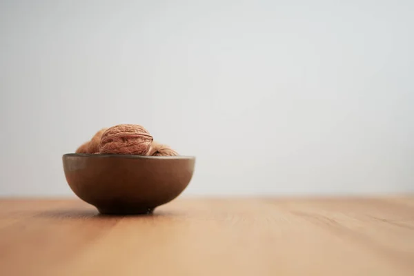 Meşe ve beyaz arka planda bronz renkli bir kasede ceviz (Juglans Regia)
