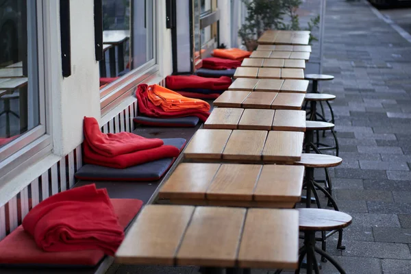 Kafe masaları sıcak kırmızı ve turuncu battaniyelerle terasa dizilmişti.