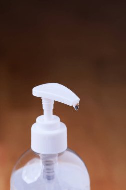 Ahşap arka planda şeffaf el dezenfektanı jeli beyaz, temiz plastik bir şişe, Coronavirus covid-19 konsepti ve el hijyeni.