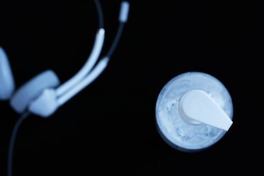 Siyah arka planda kulaklığı olan şeffaf el dezenfektanı jeli beyaz, temiz bir plastik şişe. Coronavirus covid-19 konsepti, ana ofis ve tele-çalışma, hapsedilme ve karantina.